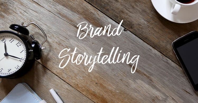 Flat lay with the words "Brand Storytelling" written on rustic wooden table surrounded by an alarm clock, smartphone, coffee cup, and stationery.