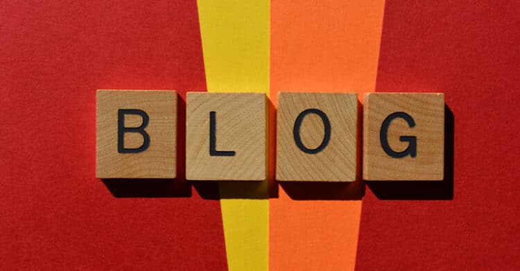 18 Ways to Write Better Blog Posts That Readers Will Finish 4 Wooden letter tiles spelling out the word "BLOG" are arranged on a bold red, orange, and yellow background. The bright color contrast draws attention to the concept of blogging, reinforcing themes around creating better blog posts.