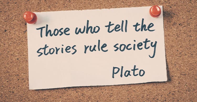 18 Ways to Write Better Blog Posts That Readers Will Finish 10 A handwritten quote on a white paper pinned to a corkboard reads, "Those who tell the stories rule society – Plato." This inspirational message underscores the power of storytelling, reinforcing its importance in writing better blog posts that influence and connect with readers.