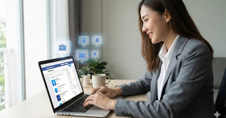 A woman in a gray blazer smiles while using a laptop displaying the Facebook Jobs platform. Floating icons for job search, location, and notifications surround her, highlighting features of the platform in a bright, modern home office setting.