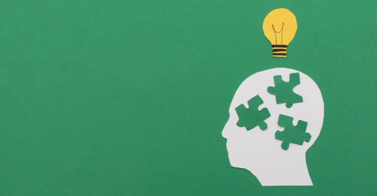 A paper cut style illustration shows a human head silhouette with missing puzzle pieces and a light bulb above it on a green background, symbolizing ideas and problem solving. The image represents strategic thinking and clarity, supporting content about developing insight and creativity to Improve Your Brand.