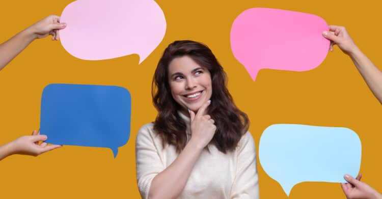 A woman stands against a mustard yellow background, smiling thoughtfully while holding her chin as colorful speech bubbles are held around her by different hands. The image represents audience feedback and messaging choices, supporting content about how listening and communication can help Improve Your Brand.