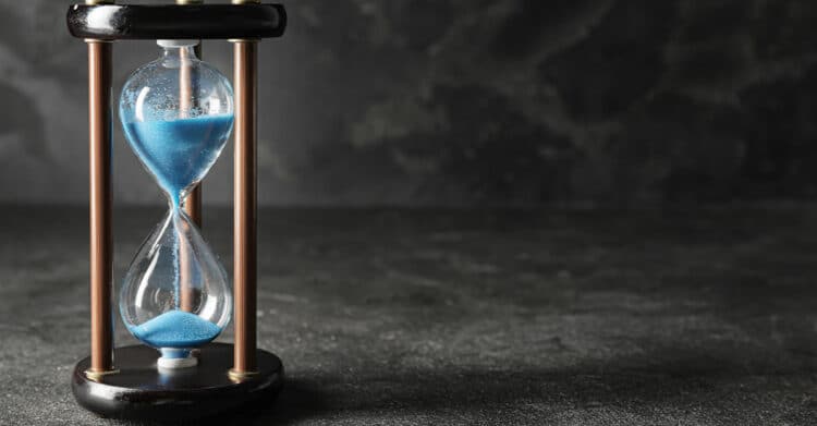 Is Your Blog Post Ready to Publish? A Complete Checklist 3 Blue sand falling through a glass hourglass on a dark surface with empty space on the right. This image can support a blog post ready for publication by visually suggesting urgency, deadlines, or limited time to act.