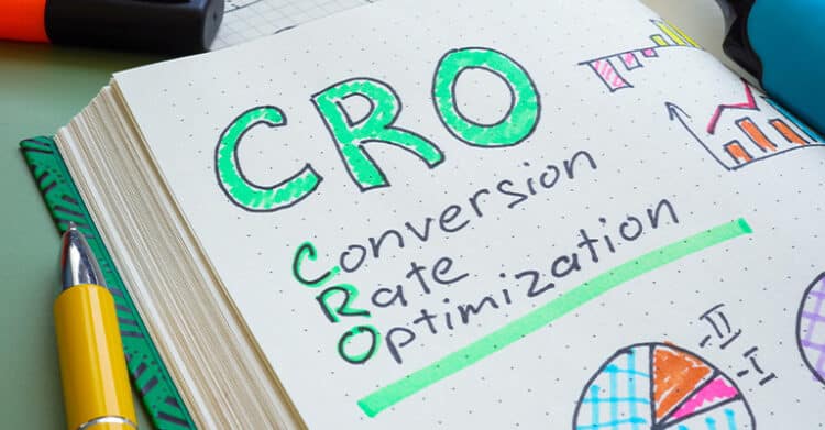 A notebook page displays the acronym “CRO” in large, colorful letters, with the words “Conversion Rate Optimization” written underneath and highlighted. Surrounded by charts, graphs, and pens, the image represents the concept of improving website performance and user conversion rates.