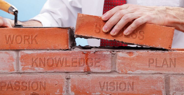 A person in business attire builds a brick wall, placing a brick labeled "SUCCESS" atop others labeled "WORK," "KNOWLEDGE," "PLAN," "PASSION," and "VISION." The image symbolizes how key attributes build the foundation for achieving success.
