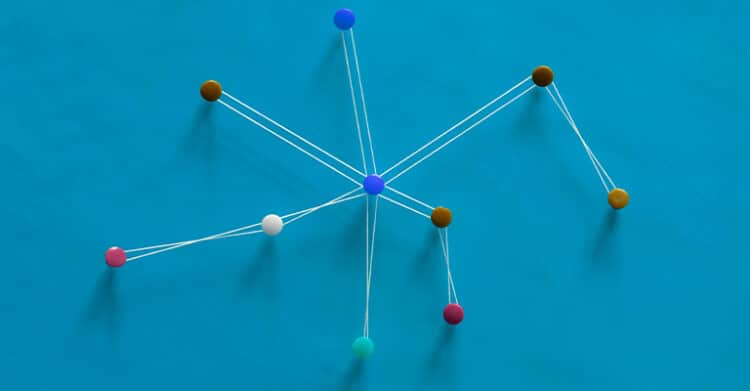 A network of colorful pins connected by white string forms a central hub on a bright blue background. The image visually represents concepts like connectivity, strategy, systems thinking, or digital networks.