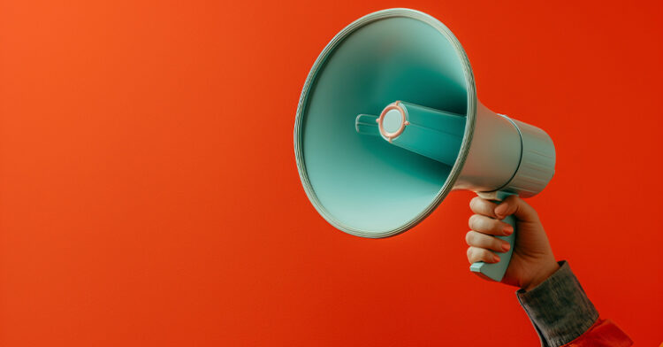 Hand holding a blue megaphone against a vibrant orange background.
