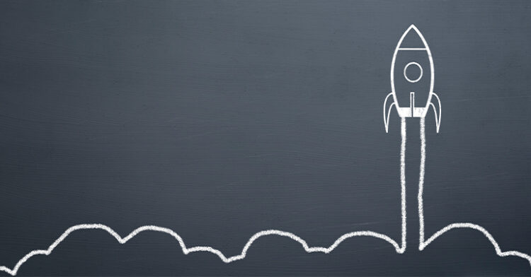 A chalk drawing of a rocket launching upward, leaving a trail of smoke, on a dark gray chalkboard background.