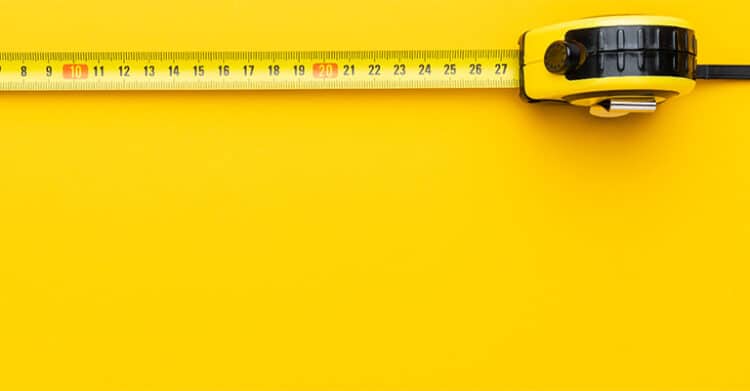 Close-up image of a yellow and black tape measure extended across a bright yellow background, with the numbers 8 to 27 visible. This image symbolizes measurement and could represent tracking metrics or measuring success in social media promotion.