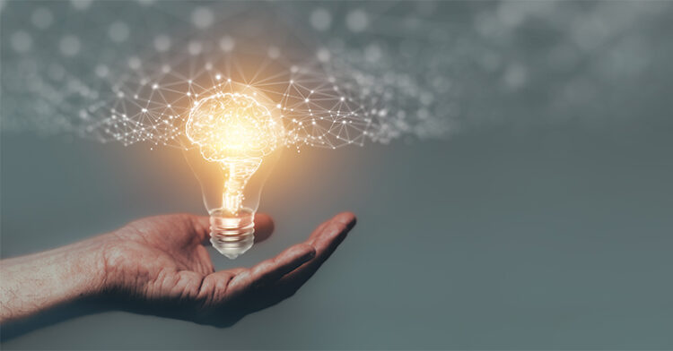 Hand holding a glowing lightbulb with a brain-shaped network of connections, symbolizing innovation and knowledge.