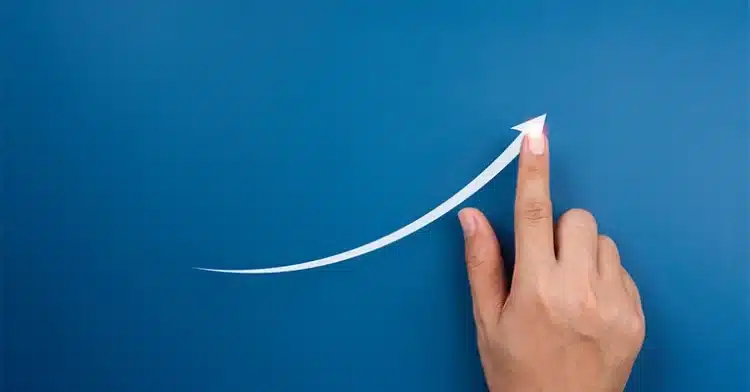 Hand pointing upward, following a white curved arrow on a blue background, symbolizing growth and progress.