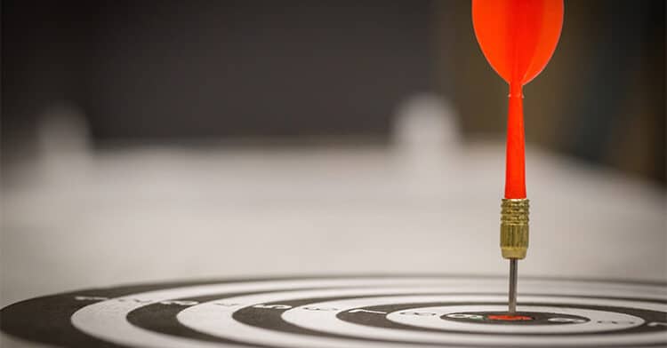 A red dart pierces the center of a black-and-white bullseye target, symbolizing precision and accurate performance tracking in marketing.
