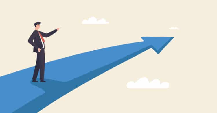Illustration of a businessman pointing forward while standing on a large blue arrow that stretches toward the sky and clouds.