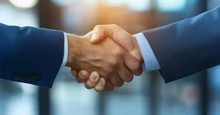 How to Use Social Media Influencers to Improve Your Marketing 7 Close-up of two people in business attire shaking hands in agreement, symbolizing partnership or collaboration.