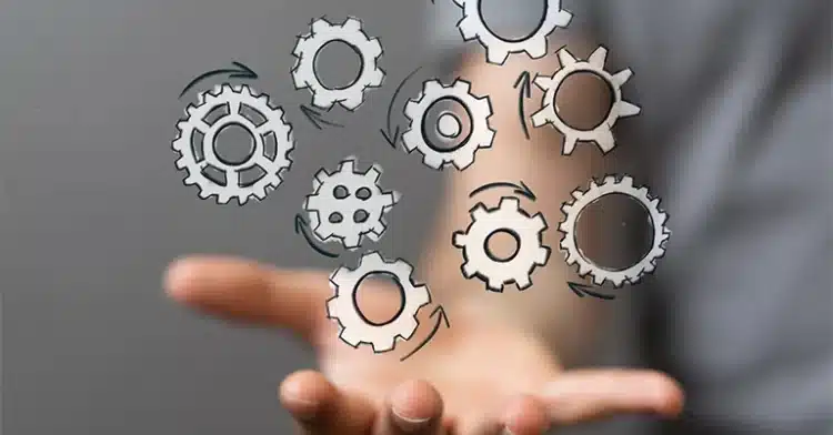 Outstretched hand beneath a floating network of illustrated gears, symbolizing interconnected systems and processes.