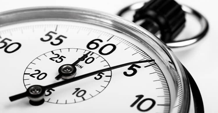 A close up view of a stopwatch face shows bold black numbers and hands pointing near the sixty second mark. The image represents timing precision tracking seconds or measuring performance and speed.