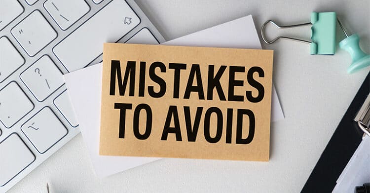 The Benefits of Blogging: Build Traffic, 10 A desk scene with a keyboard and office supplies shows a brown note card that reads MISTAKES TO AVOID in large black letters. The bold message signals a warning or checklist of common errors to watch out for.