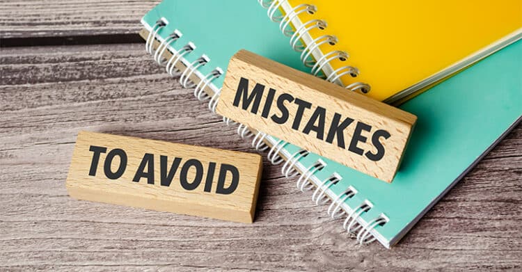 How to Build a Social Media Strategy That Works 8 Wooden blocks displaying the words "MISTAKES" and "TO AVOID" placed on top of stacked notebooks on a desk. This visual supports a social media strategy by highlighting common mistakes to avoid when planning and managing content.