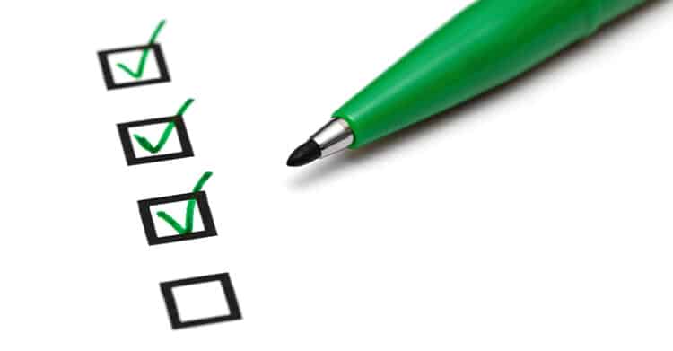 How to Build a Social Media Strategy That Works 9 Green pen marking checkboxes on a list with three boxes checked and one remaining empty. This visual supports a social media strategy by representing task completion, planning steps, and tracking progress in content execution.