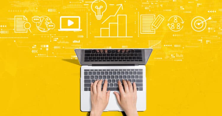 Hands type on a laptop against a bright yellow background with white icons for video, analytics, writing, audience targeting, and ideas floating above the screen. This illustration represents content marketing strategies by showing the planning, creation, and measurement of digital content.