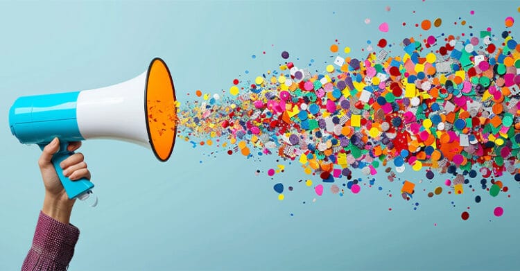 Hand holding a blue and white megaphone that blasts a stream of colorful confetti and shapes across a light blue background. The burst of attention and reach fits influencer marketing and spreading a message online.
