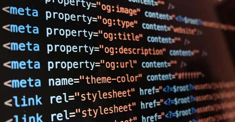 Close up of website HTML code on a dark screen showing metadata and stylesheet tags that help describe pages for search systems. Visible code includes “meta property equals og:image” “meta property equals og:type” “meta property equals og:title” “meta property equals og:description” “meta property equals og:url” “meta name equals theme-color” and “link rel equals stylesheet” connecting technical markup with answer engine optimization.