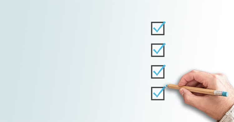 Mobile-First Indexing: How to Prepare Your Website & Content 7 Hand holding a pencil and checking off boxes on a vertical checklist against a light background, representing a mobile-first indexing checklist or audit process.