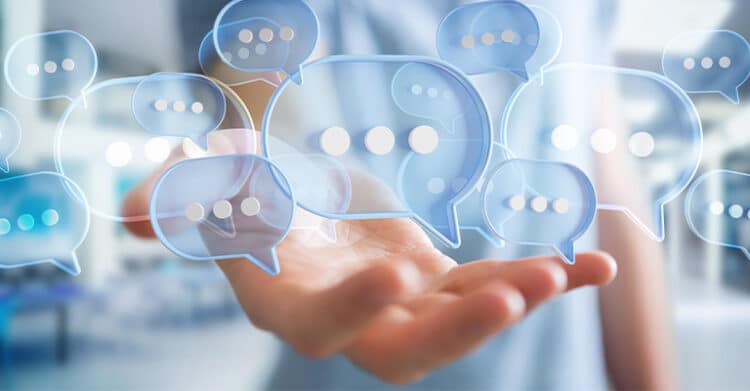 Social media marketing engagement concept showing a hand holding multiple floating digital chat bubbles representing online conversations and audience interaction.