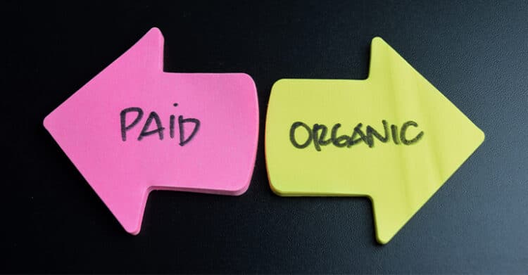Paid vs organic social media marketing comparison showing two opposing arrows — a pink arrow labeled Paid pointing left and a yellow arrow labeled Organic pointing right — on a dark background.