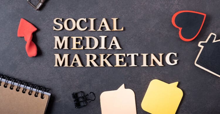 Flat lay of a desk with the words "SOCIAL MEDIA MARKETING" spelled out in wooden letters surrounded by speech bubble shapes, a notebook, and office clips. Visual for social media rules highlighting structured planning and communication strategies in marketing.