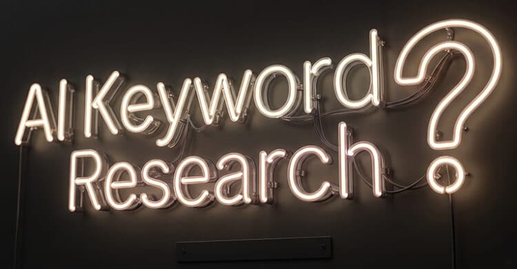 Neon wall sign reading “AI Keyword Research?” in warm white lights on a dark background. Visible wiring and mounting hardware give the sign an industrial look for content about AI keyword research.