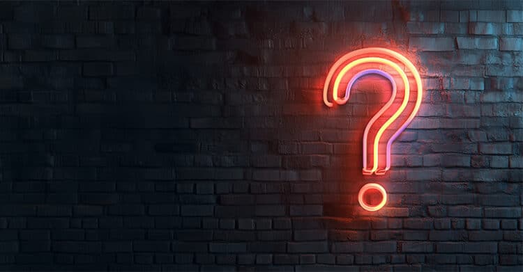 A glowing red and orange question mark hangs on a dark brick wall. It suggests the common questions readers may have about creating AI-Proof Content.